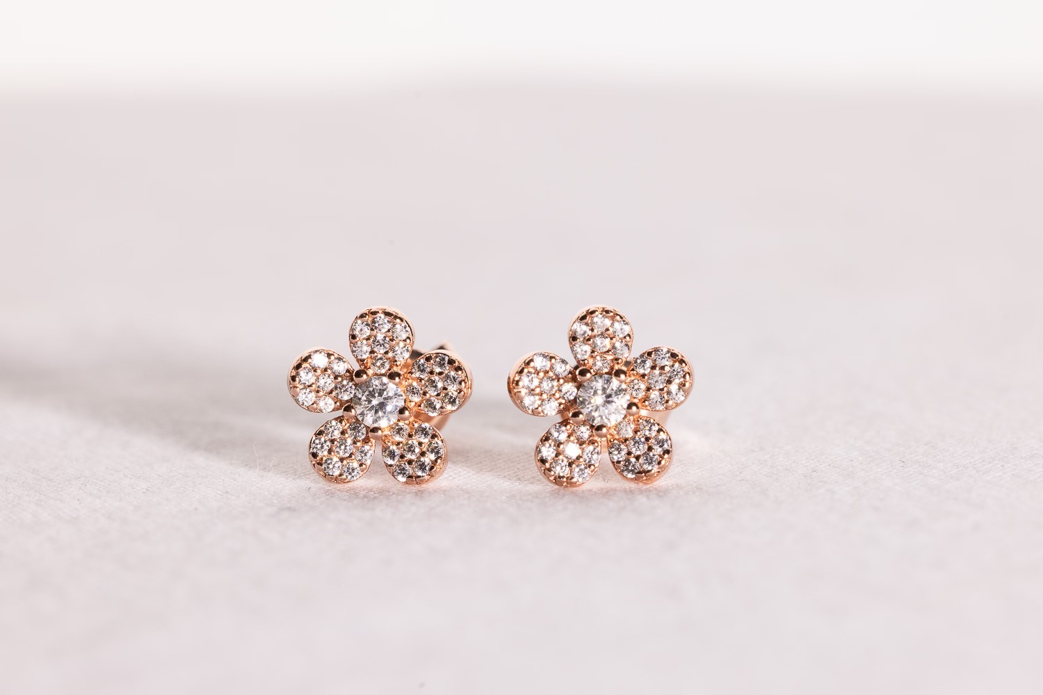 "Feel Good Flower Earrings in Rose Gold" on a white background.